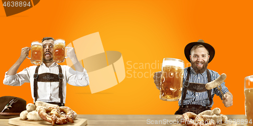 Image of Smiling men with beer dressed in traditional Austrian or Bavarian costume holding mug of beer at pub or studio. The celebration, oktoberfest, festival
