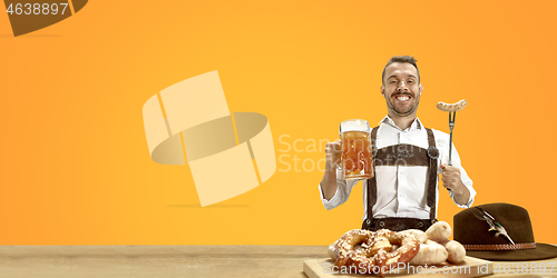 Image of Smiling man with beer dressed in traditional Austrian or Bavarian costume holding mug of beer at pub or studio. The celebration, oktoberfest, festival