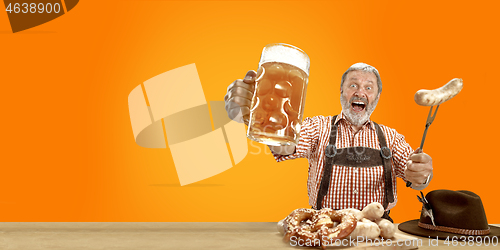 Image of Smiling senior man with beer dressed in traditional Austrian or Bavarian costume holding mug of beer at pub or studio. The celebration, oktoberfest, festival