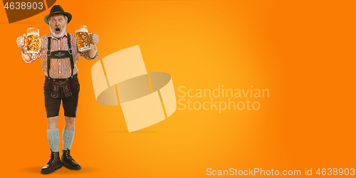 Image of Smiling senior man with beer dressed in traditional Austrian or Bavarian costume holding mug of beer at pub or studio. The celebration, oktoberfest, festival