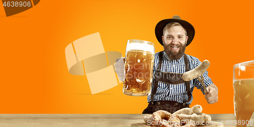 Image of Smiling man with beer dressed in traditional Austrian or Bavarian costume holding mug of beer at pub or studio. The celebration, oktoberfest, festival