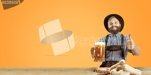 Image of Smiling man with beer dressed in traditional Austrian or Bavarian costume holding mug of beer at pub or studio. The celebration, oktoberfest, festival