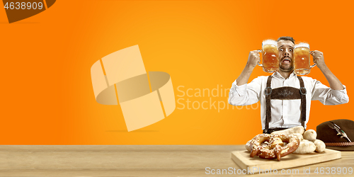 Image of Smiling man with beer dressed in traditional Austrian or Bavarian costume holding mug of beer at pub or studio. The celebration, oktoberfest, festival