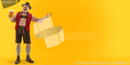 Image of Smiling senior man with beer dressed in traditional Austrian or Bavarian costume holding mug of beer at pub or studio. The celebration, oktoberfest, festival