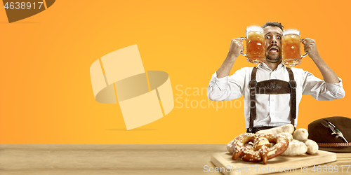 Image of Smiling man with beer dressed in traditional Austrian or Bavarian costume holding mug of beer at pub or studio. The celebration, oktoberfest, festival