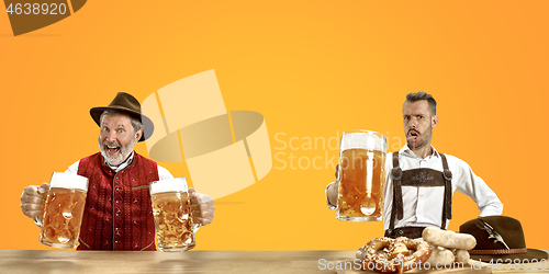 Image of Smiling men with beer dressed in traditional Austrian or Bavarian costume holding mug of beer at pub or studio. The celebration, oktoberfest, festival