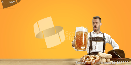 Image of Smiling man with beer dressed in traditional Austrian or Bavarian costume holding mug of beer at pub or studio. The celebration, oktoberfest, festival