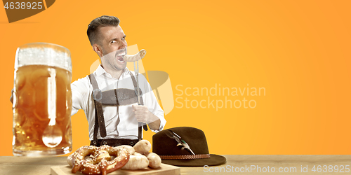 Image of Smiling man with beer dressed in traditional Austrian or Bavarian costume holding mug of beer at pub or studio. The celebration, oktoberfest, festival