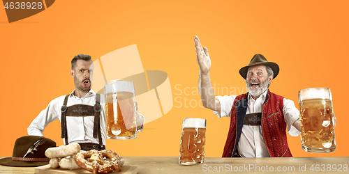 Image of Smiling men with beer dressed in traditional Austrian or Bavarian costume holding mug of beer at pub or studio. The celebration, oktoberfest, festival