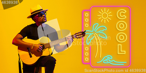 Image of Young musician playing guitar in neon light on gradient background, inspired, artwork