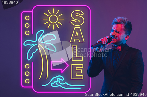 Image of Young musician, party host singing, dancing in neon light