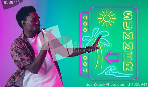 Image of Young musician, party host singing, dancing in neon light