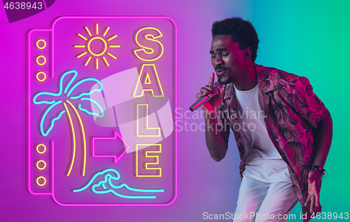 Image of Young musician, party host singing, dancing in neon light