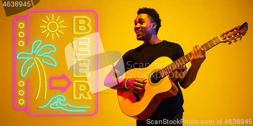 Image of Young musician playing guitar in neon light on gradient background, inspired, artwork