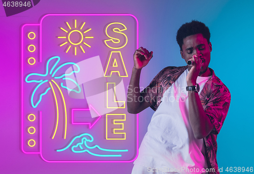 Image of Young musician, party host singing, dancing in neon light