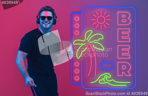 Image of Young musician, party host singing, dancing in neon light