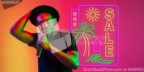 Image of Young musician, party host singing, dancing in neon light