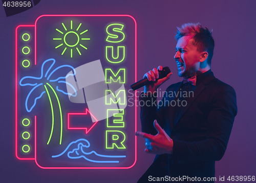 Image of Young musician, party host singing, dancing in neon light