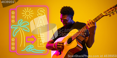 Image of Young musician playing guitar in neon light on gradient background, inspired, artwork