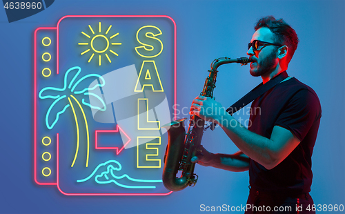 Image of Young jazz musician playing the saxophone in neon light with neon sign