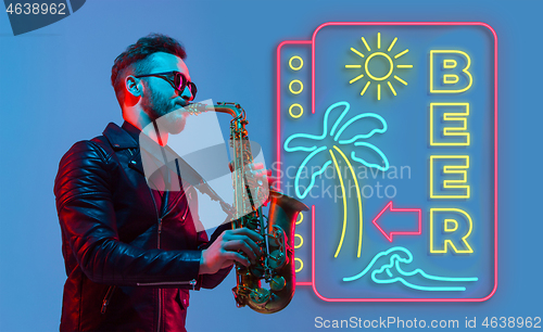 Image of Young jazz musician playing the saxophone in neon light with neon sign