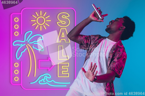 Image of Young musician, party host singing, dancing in neon light