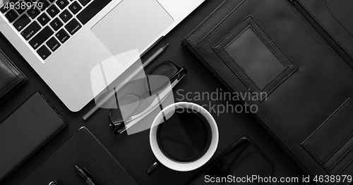 Image of Business desktop concept. Mix of office supplies and gadgets on a black table background