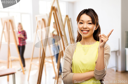 Image of happy asian woman pointing finger up