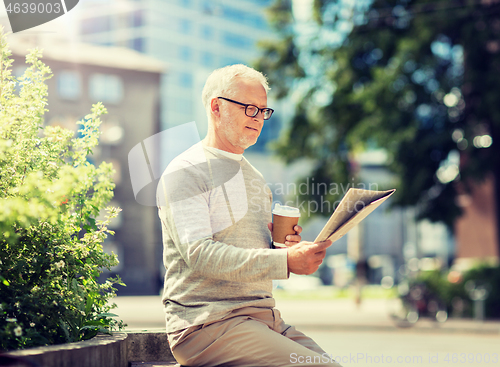 Image of senior man reading newspaper and drinking coffee