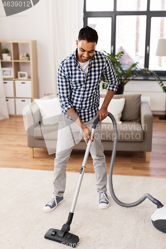 Image of indian man with vacuum cleaner at home