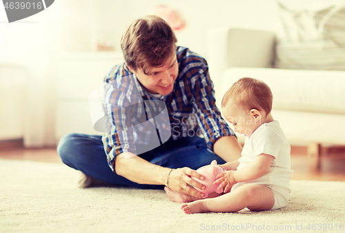 Image of happy father with baby and piggy bank at home