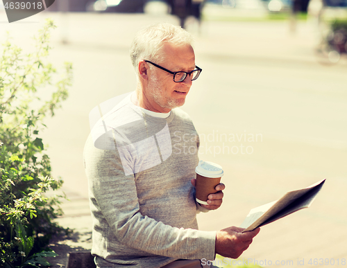 Image of senior man reading newspaper and drinking coffee