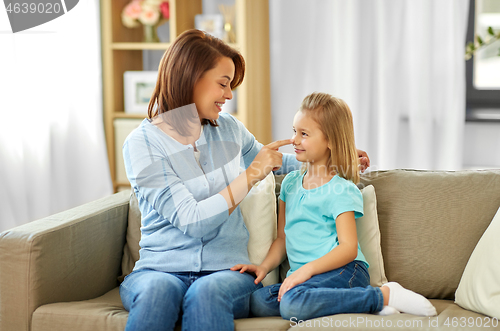 Image of mother and daughter sitting on sofa at home