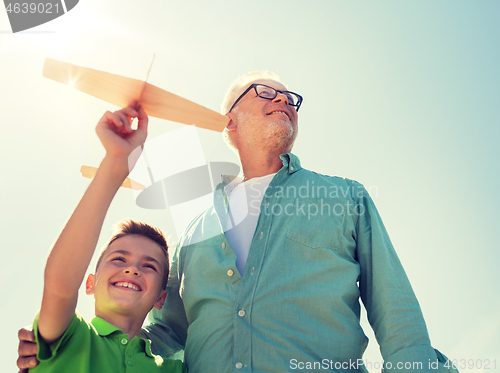 Image of senior man and boy with toy airplane over sky