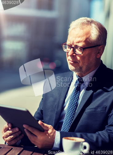 Image of senior businessman with tablet pc drinking coffee