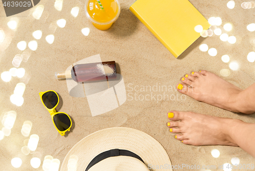 Image of feet, hat, shades, sunscreen and juice on beach