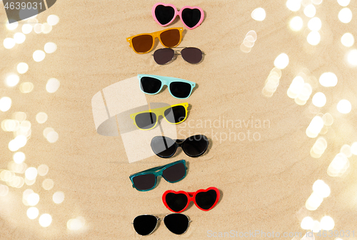 Image of different sunglasses on beach sand