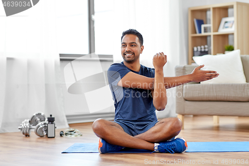 Image of man training and stretching arm at home