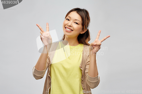 Image of happy asian woman showing peace