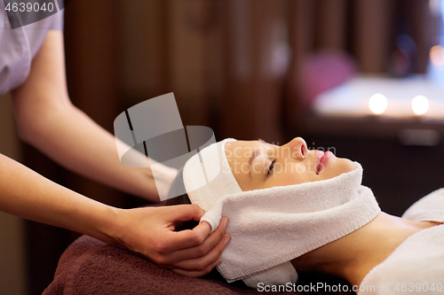 Image of woman having face massage with towel at spa