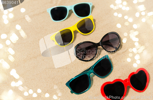 Image of different sunglasses on beach sand