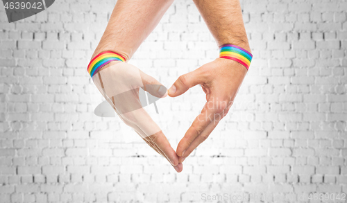 Image of male hands with gay pride wristbands showing heart