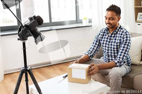 Image of male video blogger opening parcel box at home