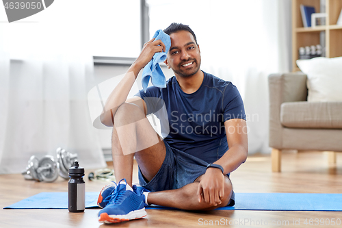 Image of tired indian man with towel after training at home