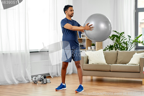 Image of indian man exercising with fitness ball at home