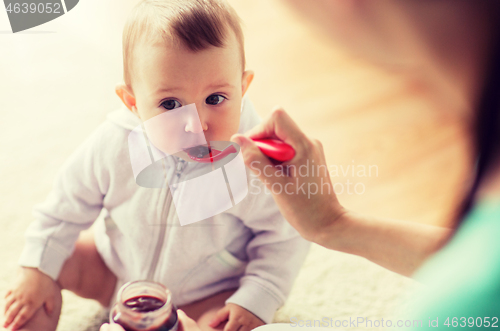 Image of mother with spoon feeding little baby at home