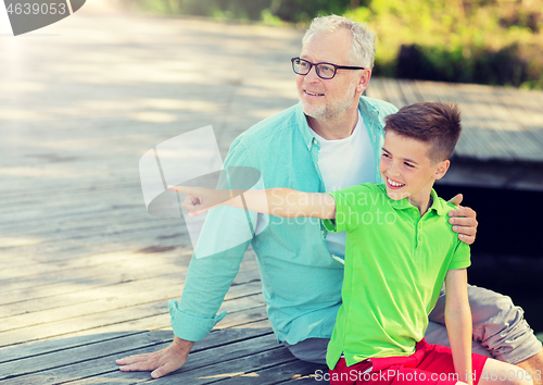 Image of grandfather and grandson sitting on river berth