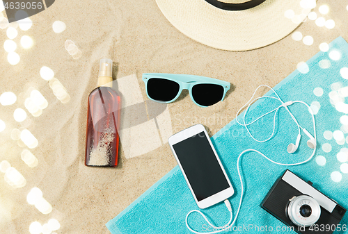 Image of smartphone, camera, towel, hat and shades on beach