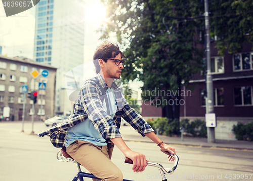 Image of young hipster man with bag riding fixed gear bike