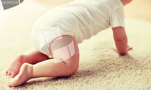 Image of little baby in diaper crawling on floor at home